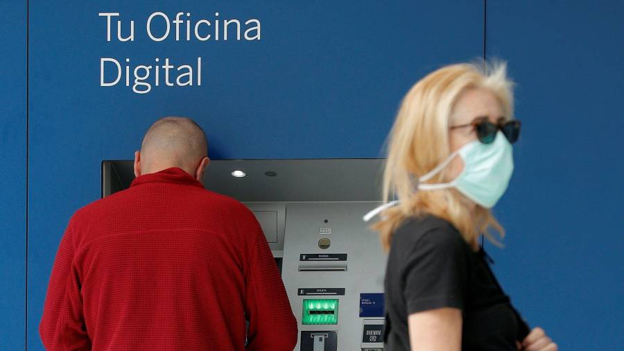 Dos personas, frente al cajero automático de un banco.  FOTO: EFE