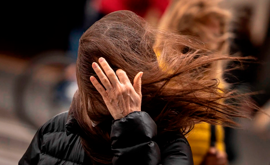 Una mujer intenta quitarse el cabello de la cara empujado por el viento. Foto: EFE